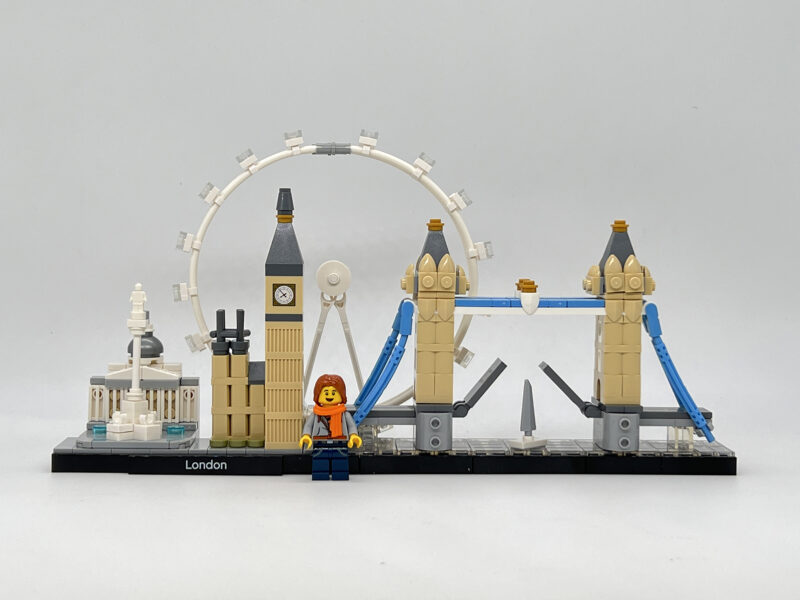 Lego Sam stands in front of a London scene excited to go on the Embroidered Journey London Retreat!
