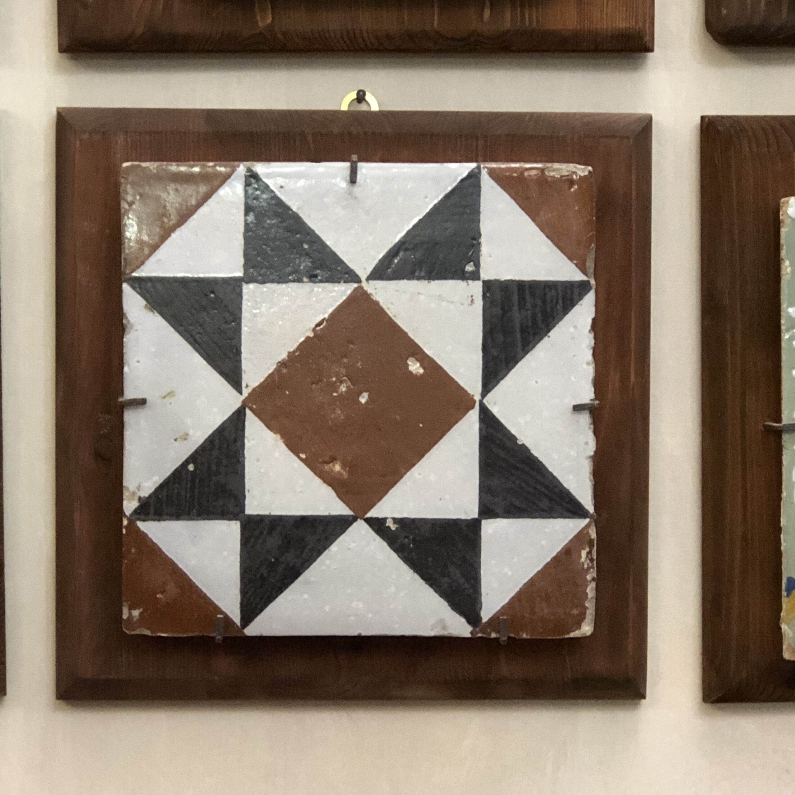 A sawtooth star is featured on a tile in brown and black. Seen at Museo Della Maioliche, also know as the Museum of Tiles.
